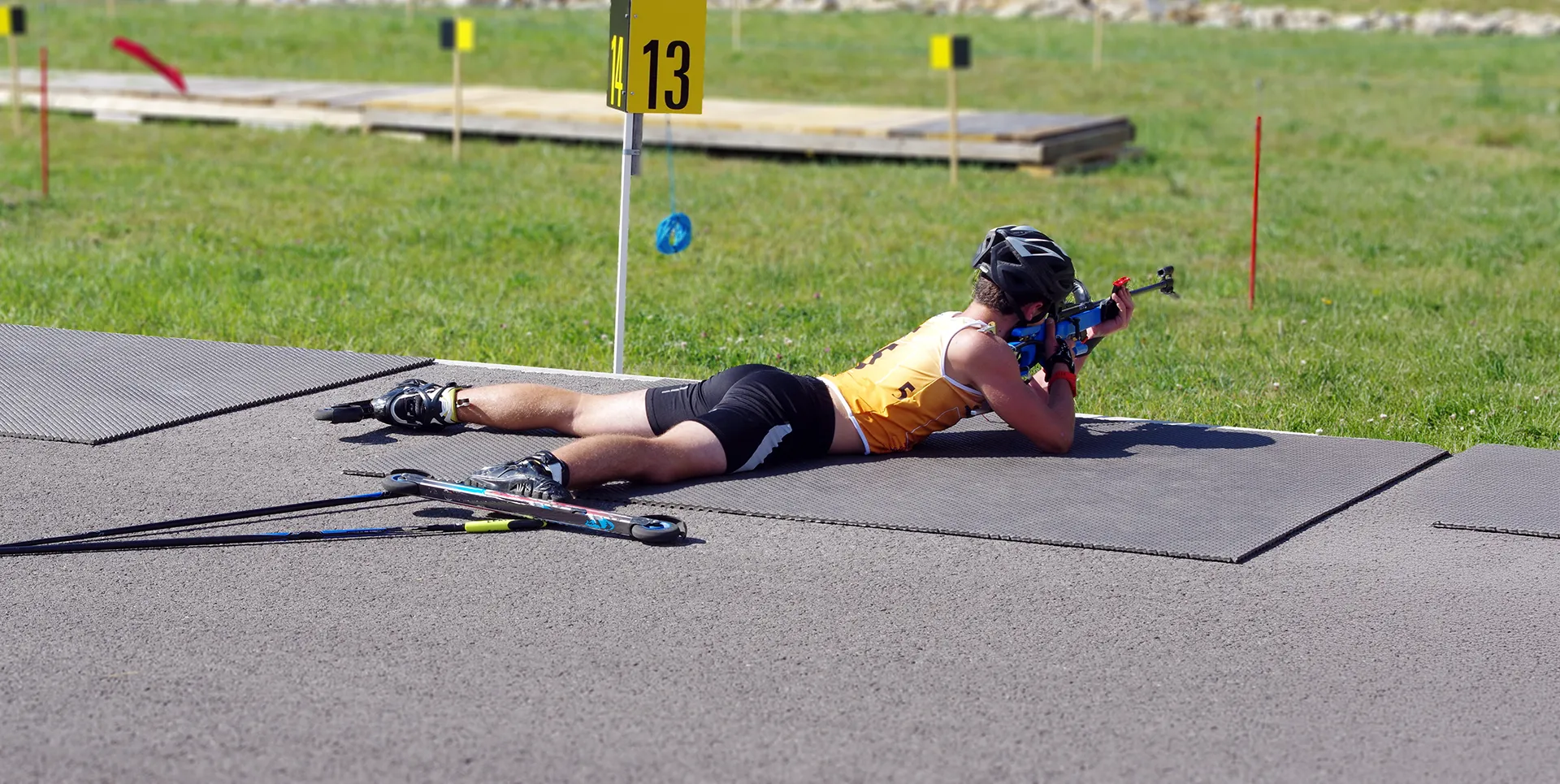 Ein Sommerbiathlet liegt am Schießstand und zielt mit seinem Gewehr